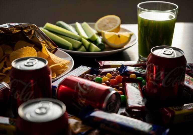 Contrasting Image Of Junk Food In Focus And A Fresh Detox Snack In The Background, Symbolizing Clean Eating Choice.