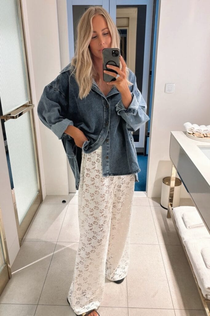 How To Style Oversized Shirts Like A Fashion Blogger 14 Woman Wearing An Oversized Denim Shirt Over White Lace Pants, Posing In A Mirror.
